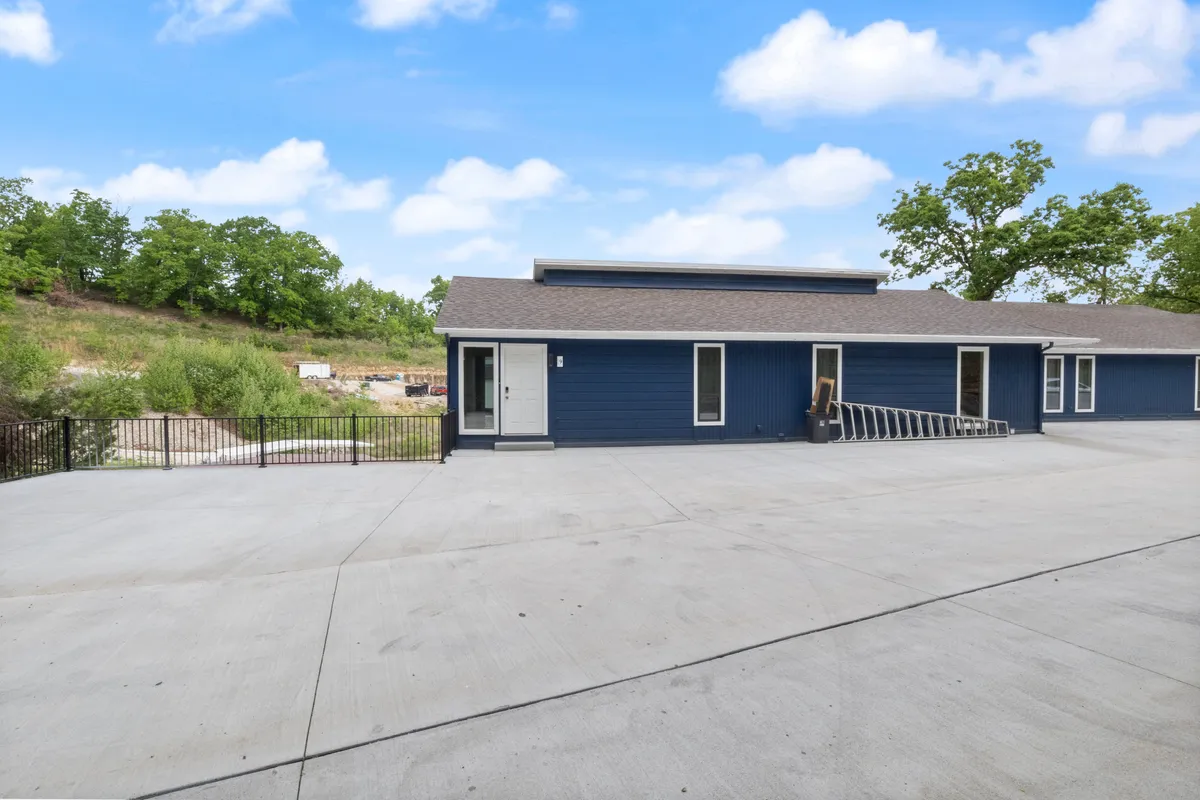 A broad view of the property’s modern exterior and clean concrete driveway encircled by vibrant greenery. The serene environment hints at nearby trails and the ease of setting off for local pet-friendly adventures.