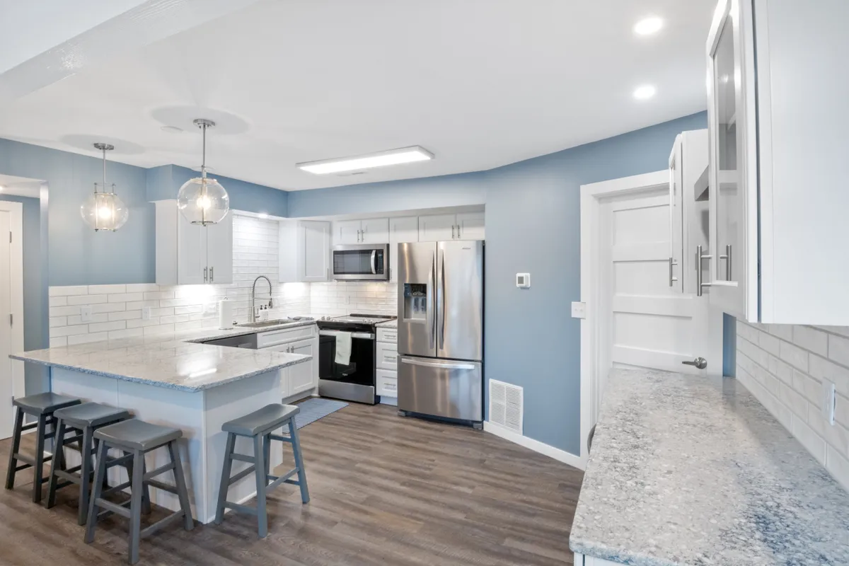 A spacious, modern kitchen featuring a large island with seating, stainless steel appliances, granite countertops, and stylish pendant lighting. The open concept allows for easy interaction with adjacent living and dining spaces, making it ideal for both family meals and entertaining guests.