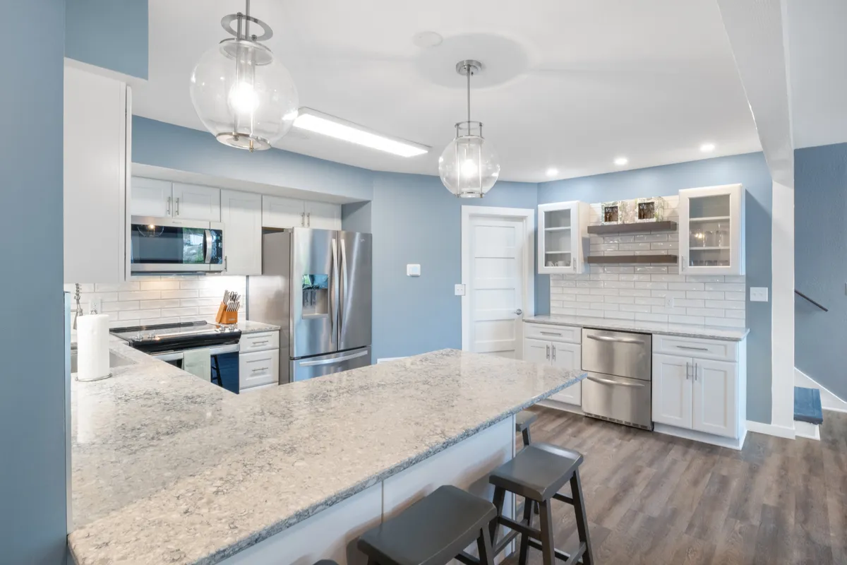 A bright kitchen scene with a sleek granite countertop, contemporary light fixtures, and a central island that provides plenty of space for meal prep and informal gatherings. The design conveys a modern, functional, and inviting atmosphere.